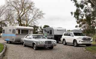 Two cars and caravans parked in front of a farm